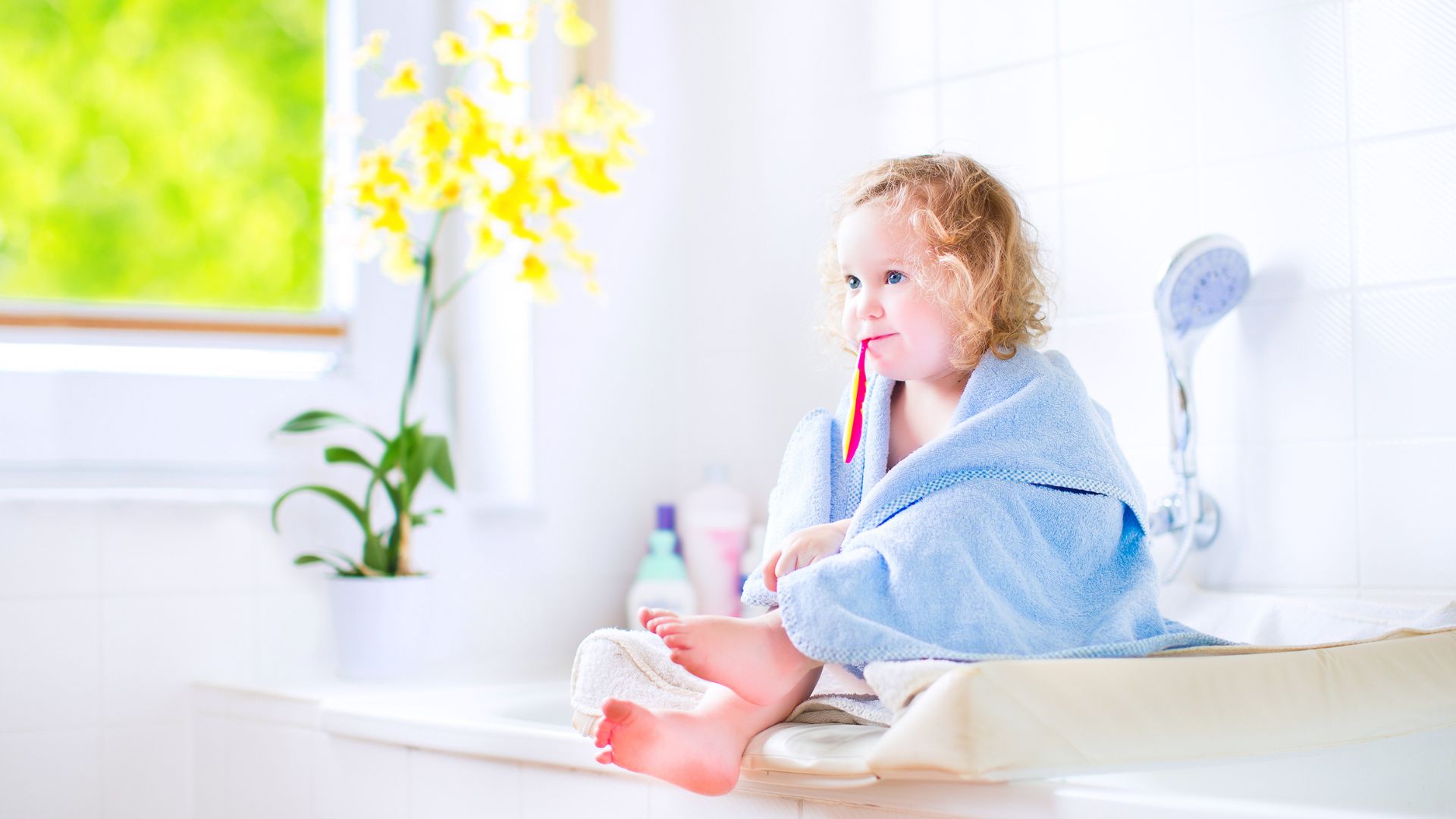A Small Baby, Wrapped in a Soft Towel, Brushes Her Teeth